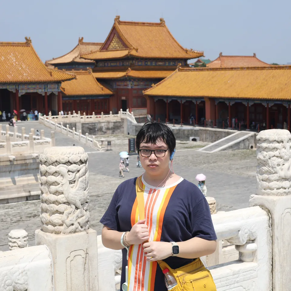 Marceline Belardo wearing glasses in a courtyard with golden-roofed buildings