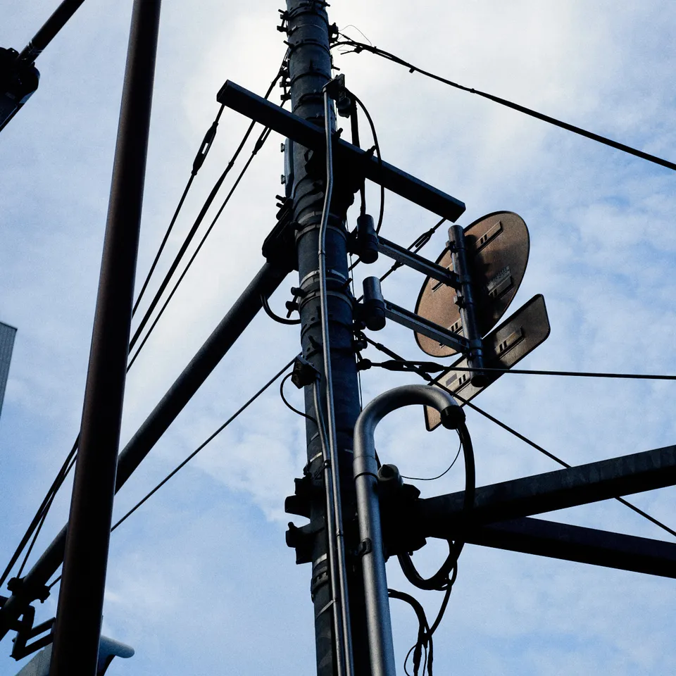 Utility poles and overhead wires against a blue sky in Tokyo