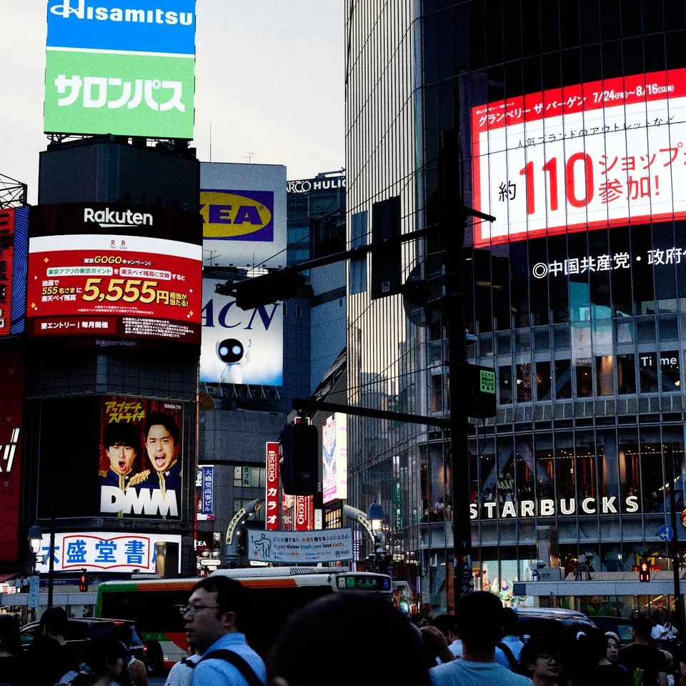 Crowds beneath colorful billboards and storefronts in Shibuya, Tokyo